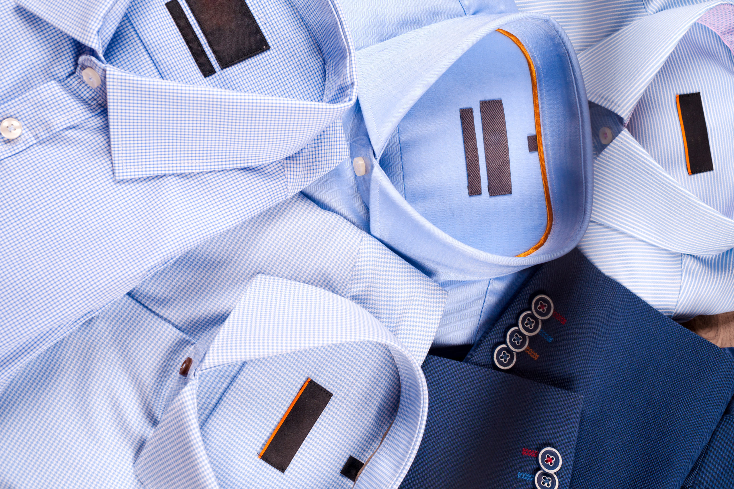 Flat lay set of classic mens clothes such as blue suit, shirts, brown shoes, belt and tie on wooden background. Men's accessories set. Top view. Copy space for text.